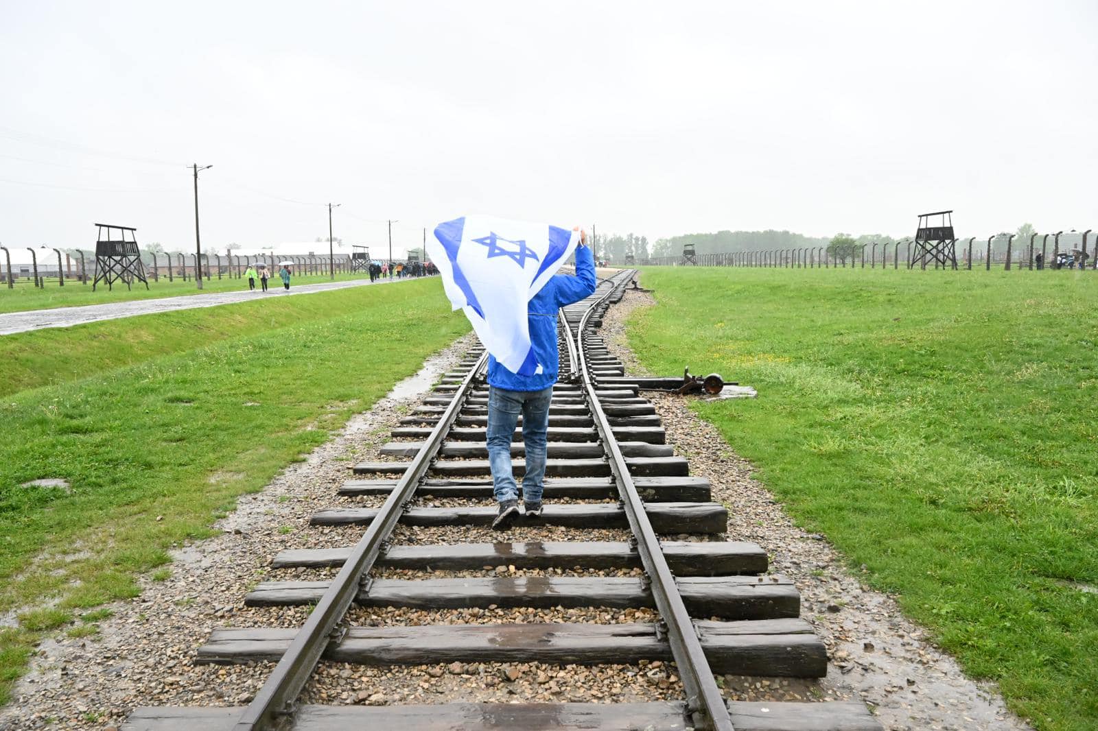 פוסעים על פסי הרכבת המובילים לאושוויץ תוך הנפת דגל ישראל
